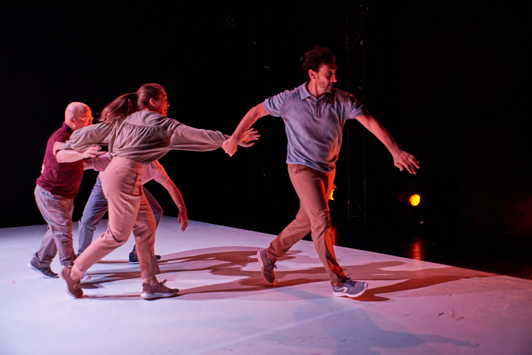 Alle vier Tänzer*innen der Performance halten sich an den Armen oder Händen fest und rennen in einem Pulk über die Bühne.
